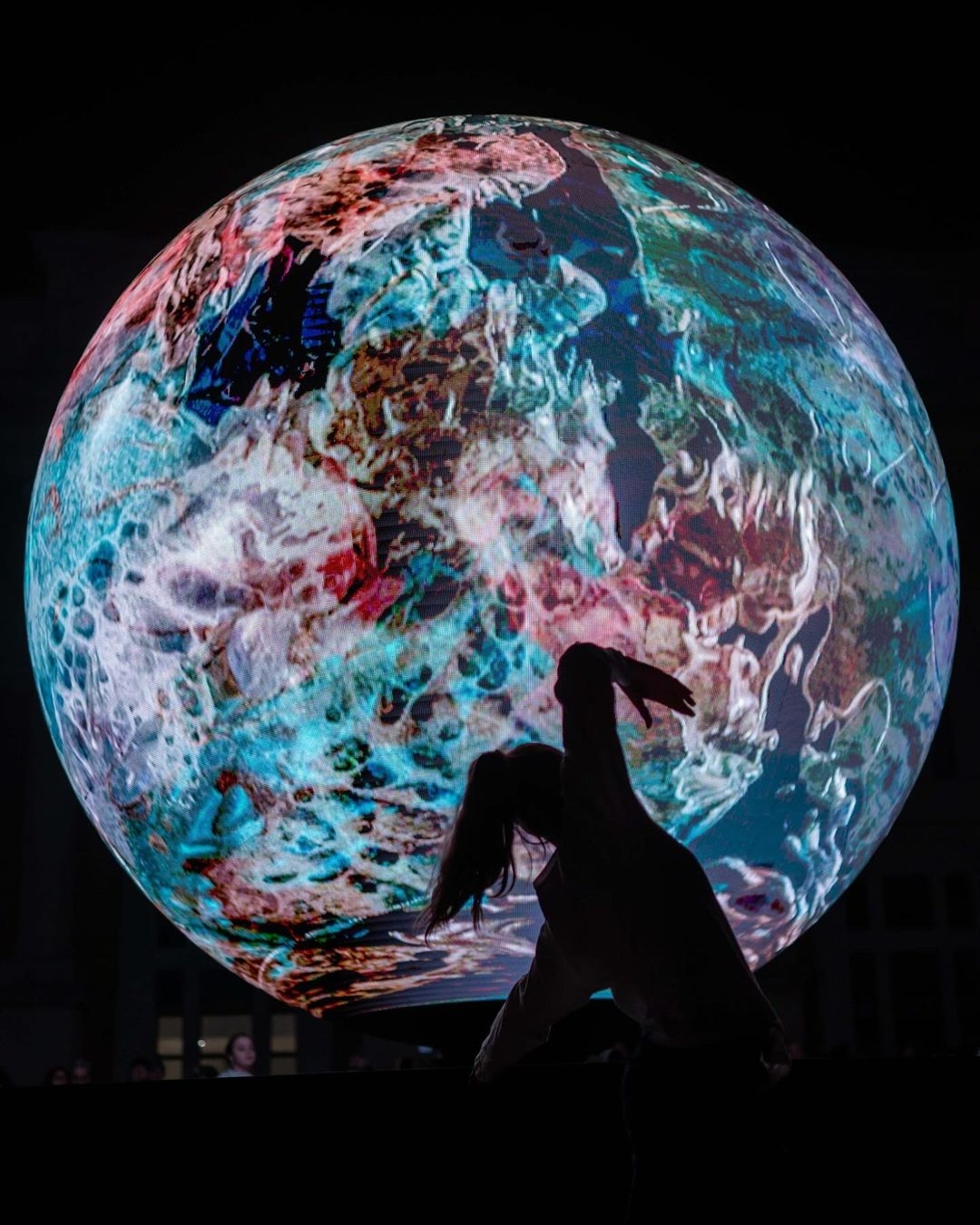 Danzatrice che balla di fronte alla Biosfera di Pesaro, un'installazione scultoreo-digitale