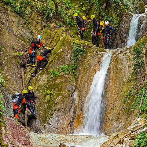Escursionisti si arrampicano su una montagna accanto ad una piccola cascata.