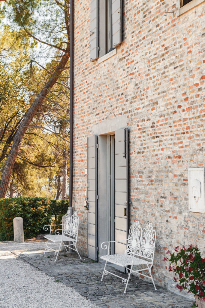 Main entrance of Pignocco Country House with two white iron benches, leading to the reception.