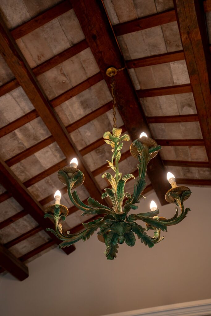 Un lampadario rivestito da tante piccole decorazioni a forma di foglia, di colore verde e con sfumature oro.