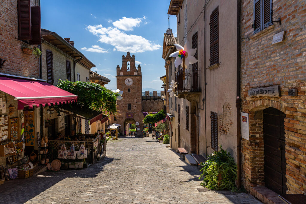 La torre dell’orologio e la via principale di Gradara, con negozi di souvenir in un’atmosfera dal fascino antico.