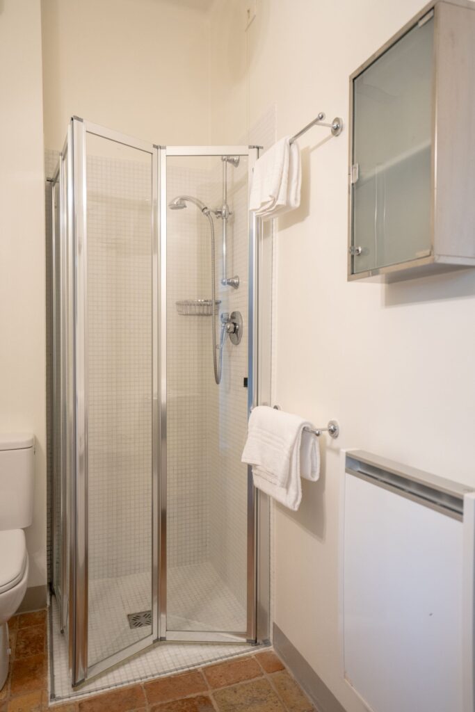 Corner shower made of glass and aluminum.