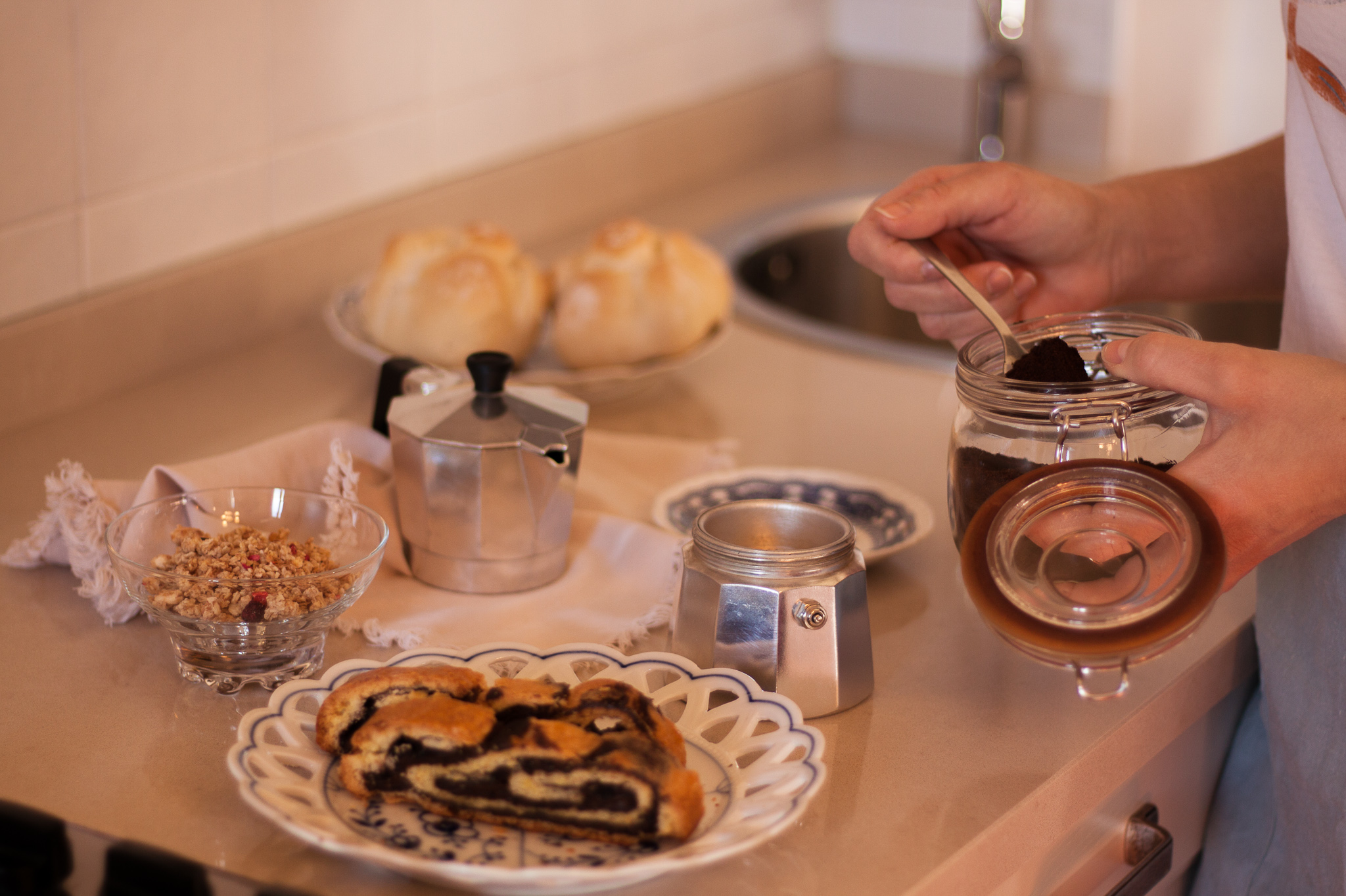 Preparazione del caffè mattutino con la tradizionale moka italiana, dolci, pane, cereali, disposti sul piano della cucina